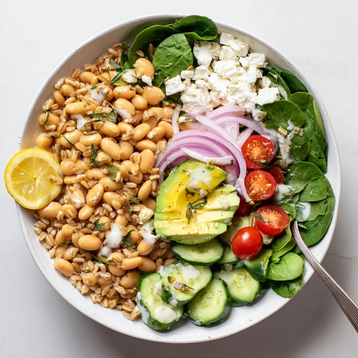 Hearty farro grain bowl featuring creamy roasted garlic butter beans with crisp cucumber cherry tomatoes avocado