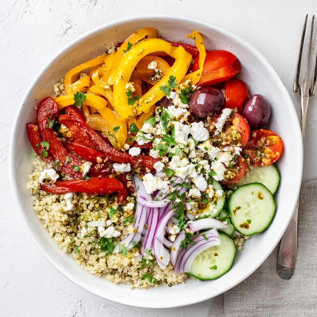 Colorful Mediterranean roasted pepper quinoa grain bowl topped with creamy feta and fresh vegetables