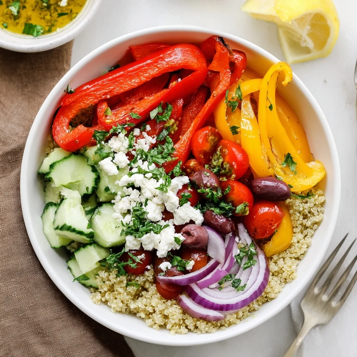 Fluffy quinoa bowl layered with charred roasted peppers crisp cucumbers and crumbled feta cheese