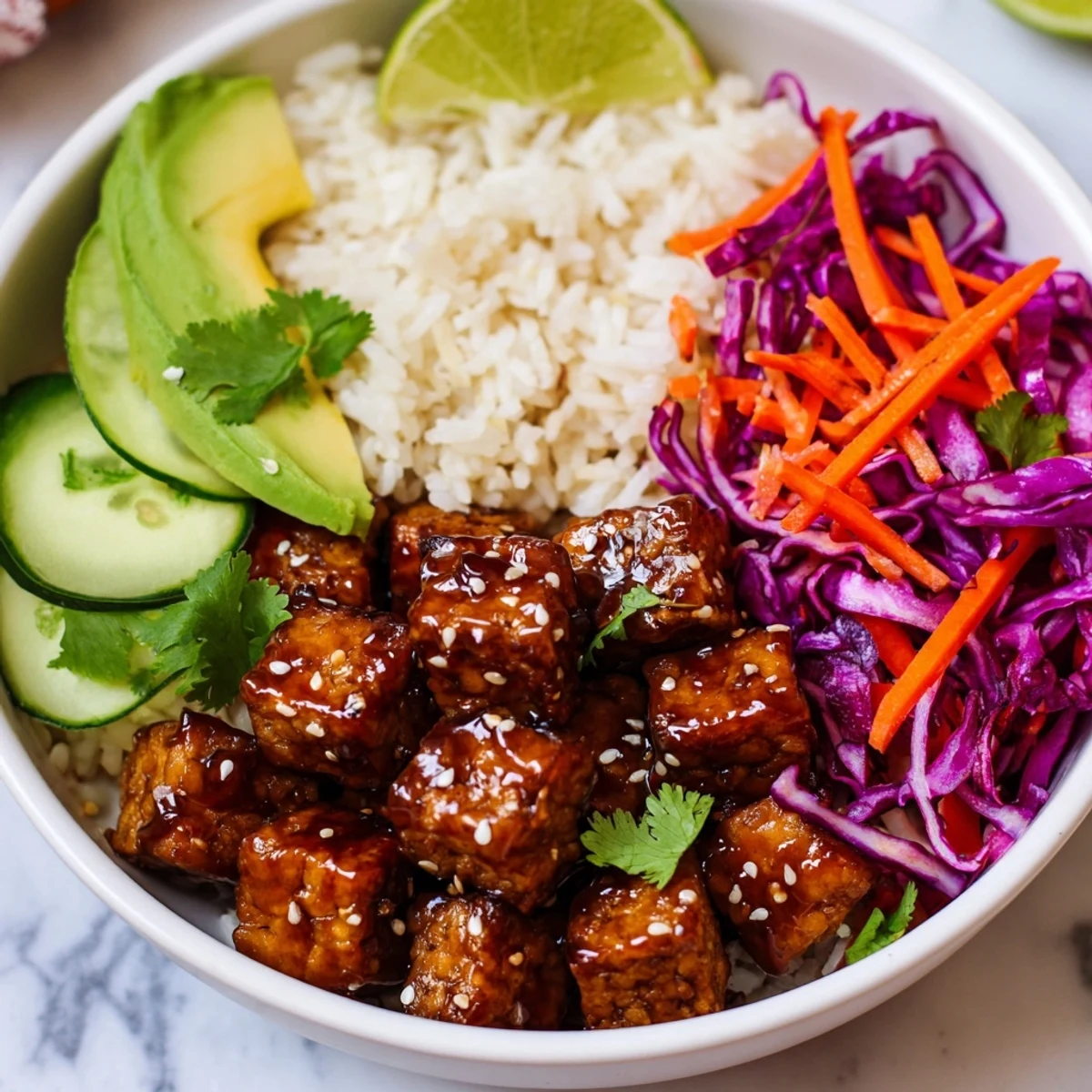 Protein-packed maple Sriracha tempeh bowl featuring crunchy red cabbage, carrots, cucumber, and fresh cilantro garnish