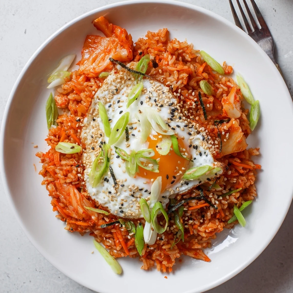 Reddish tinged kimchi rice scattered with green scallions and nutty sesame topping