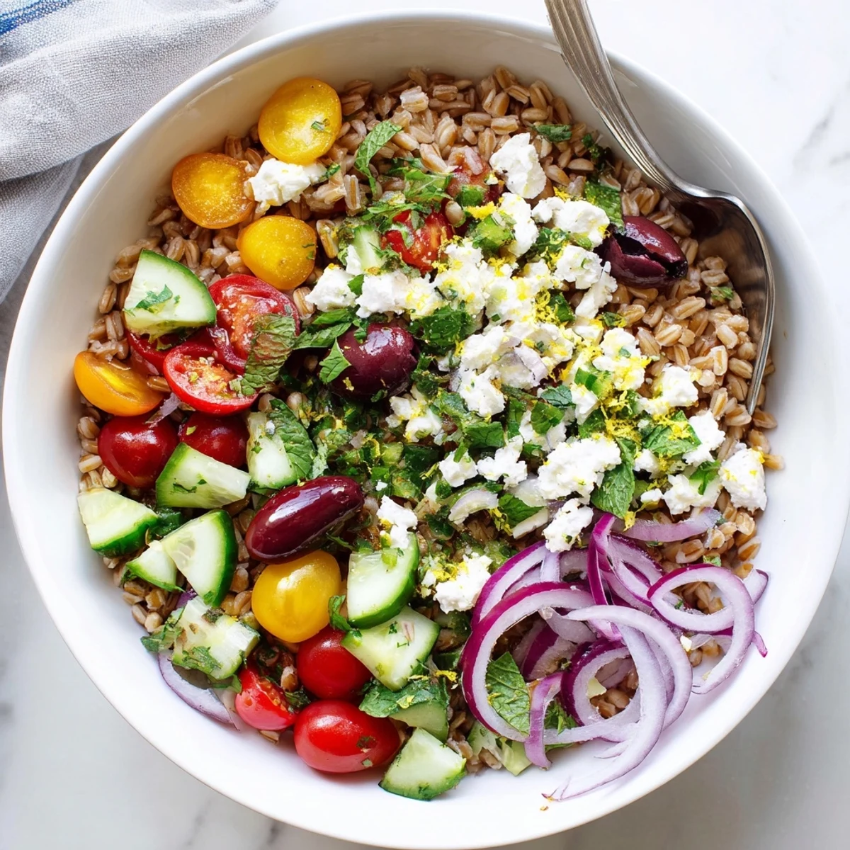 Hearty bowl of nutty farro mixed with cherry tomatoes, cucumber, and tangy lemon herb dressing