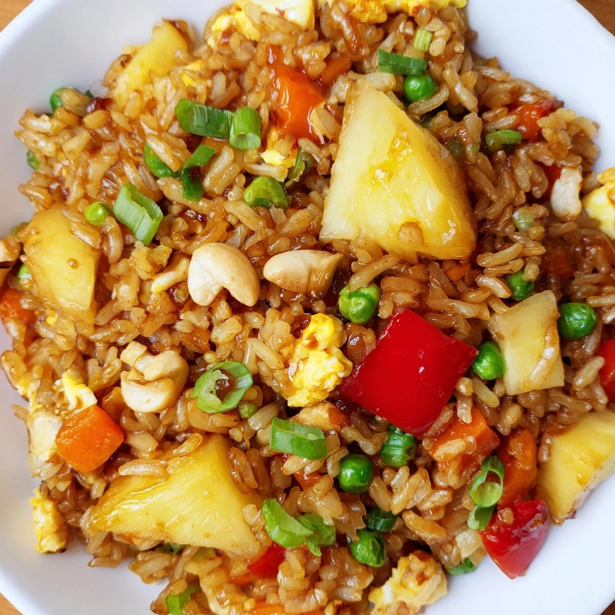 Golden sweet chili pineapple fried rice with colorful vegetables and fresh scallions garnish