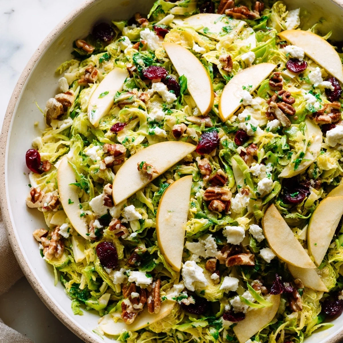 Crisp Brussels sprout apple salad with cranberries pecans and tangy maple Dijon dressing