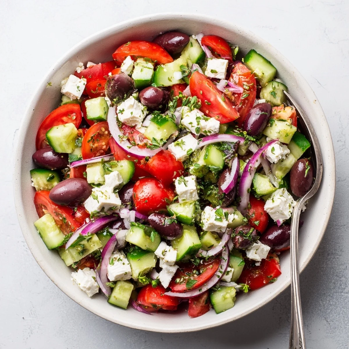 Vibrant Mediterranean tomato cucumber feta salad bowl drizzled with olive oil dressing and fresh herbs