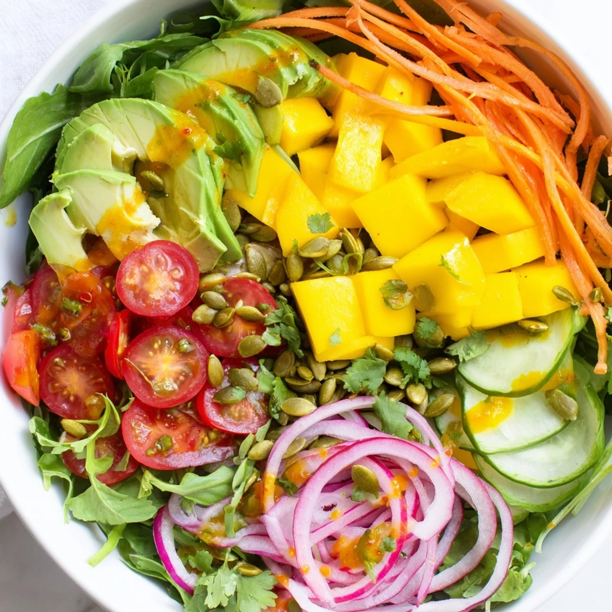 Fresh mango avocado veggie bowl topped with crisp vegetables and creamy chili lime sauce in a vibrant layered presentation