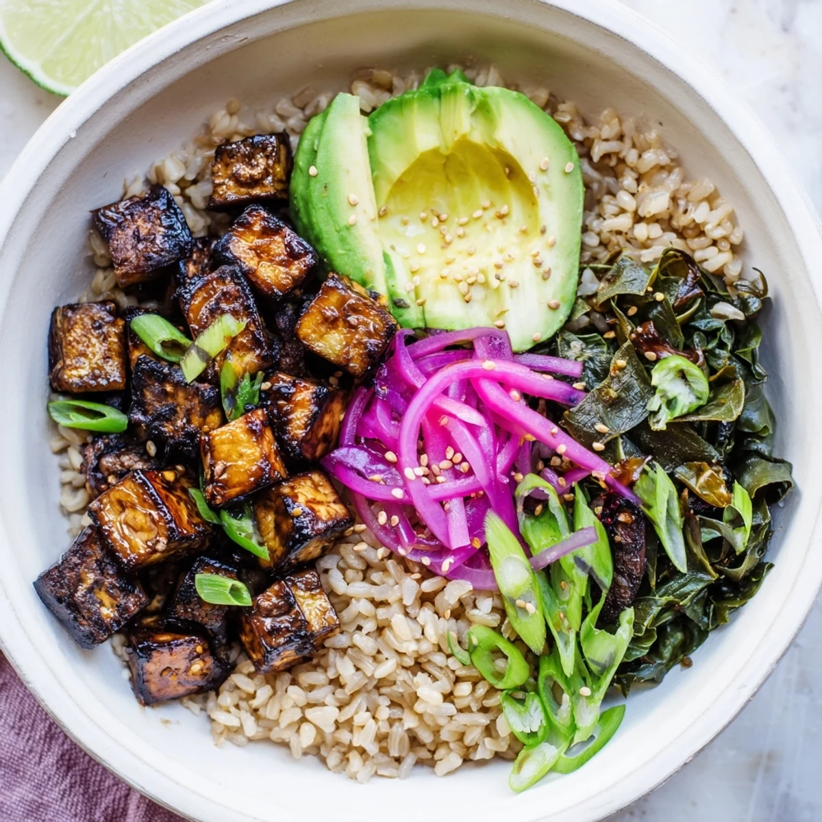 Close-up of glossy maple miso roasted eggplant cubes atop a bed of sesame greens