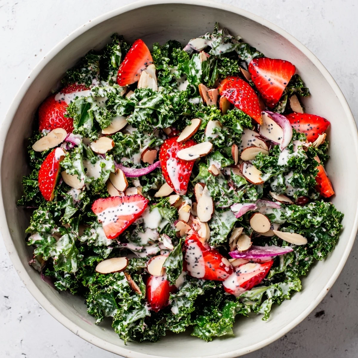 Vibrant salad bowl with crispy kale strawberries almonds and poppyseed drizzle ready to serve
