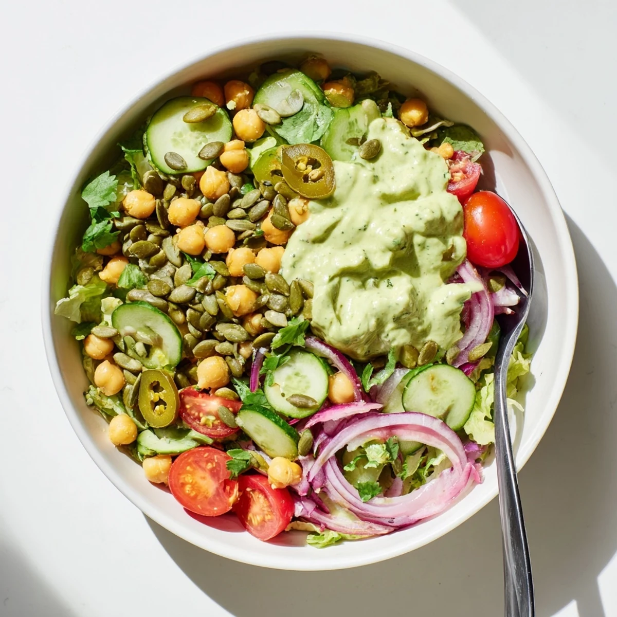 Hearty chickpea salad bowl drizzled with zesty avocado lime dressing and garnished with cilantro