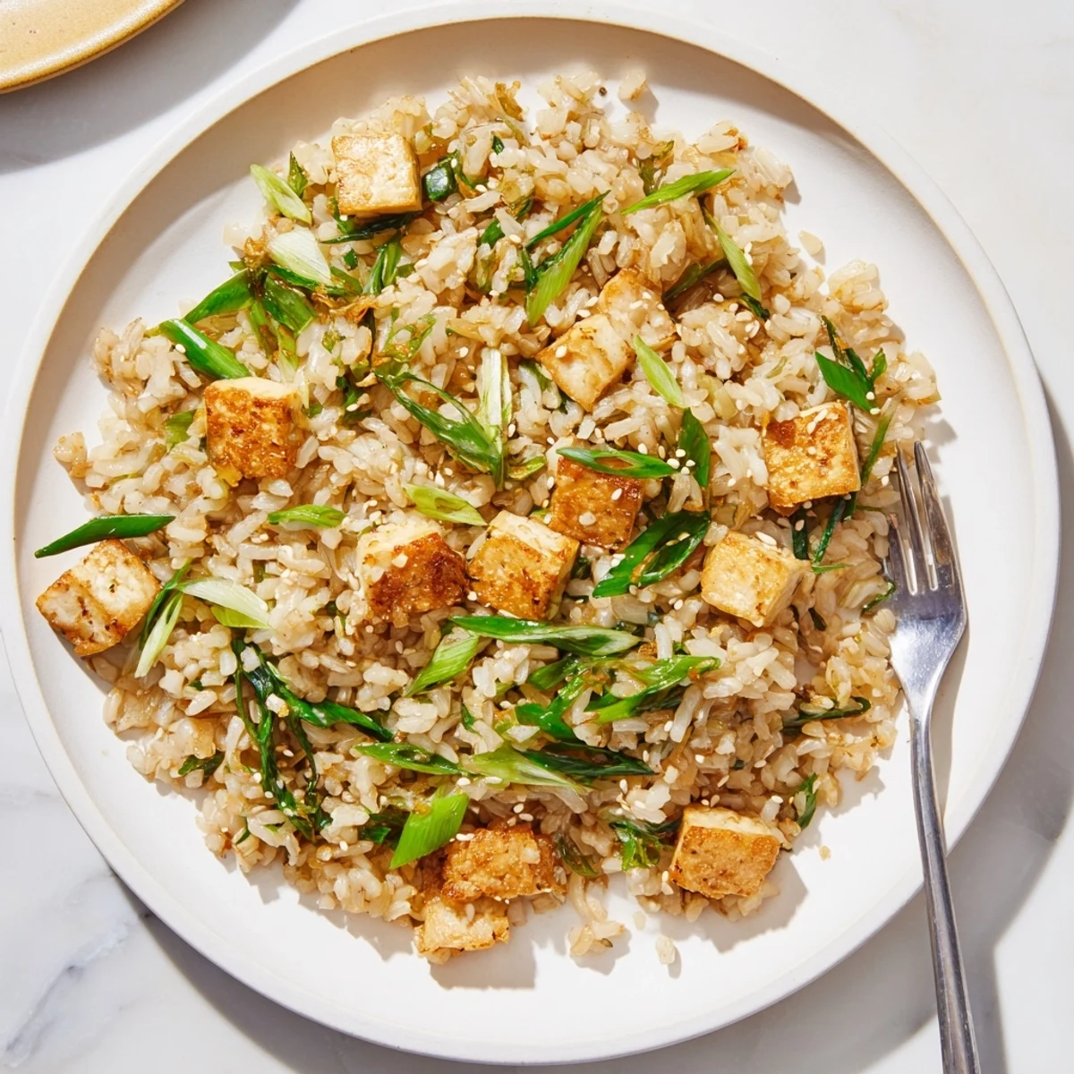 Golden crispy tofu cubes arranged over fragrant garlic ginger scallion rice in a white bowl
