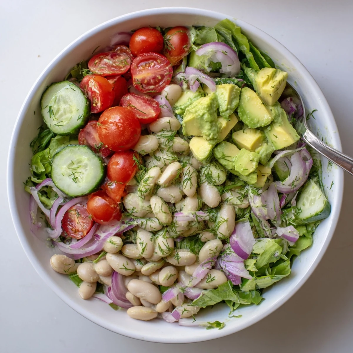 Creamy dill avocado white bean salad bowl with fresh vegetables and zesty lemon drizzle