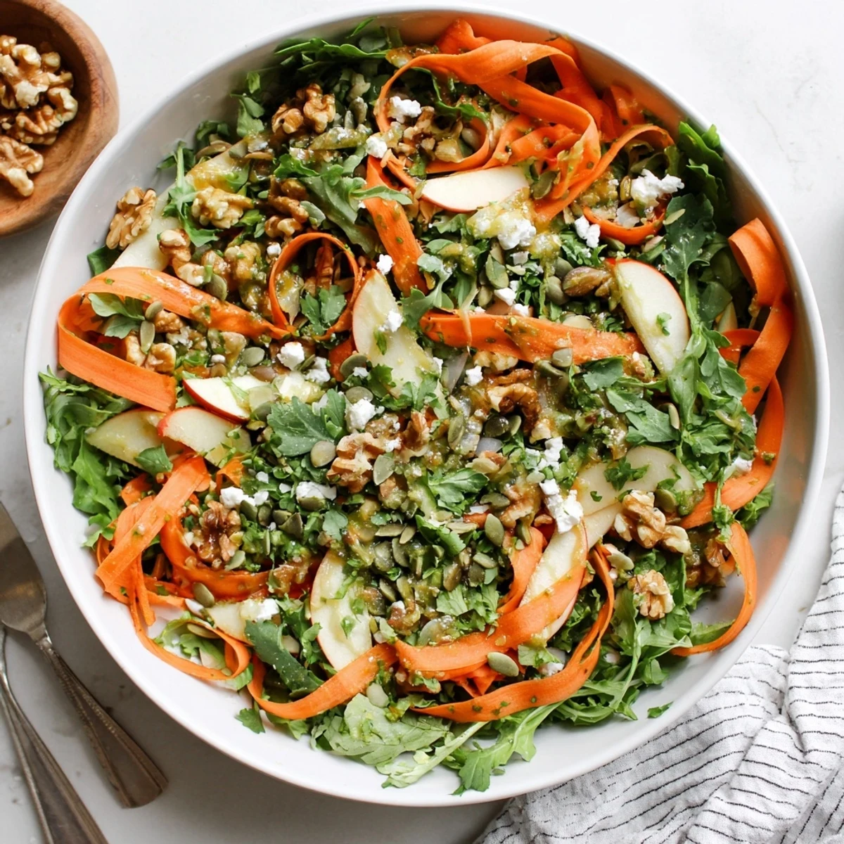 Vibrant shaved carrot and apple salad bowl topped with crunchy walnuts maple dressing
