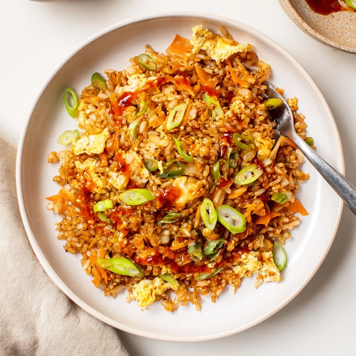 Steaming bowl of kimchi chili crisp fried rice topped with aromatic scallions and red pepper flakes for garnish