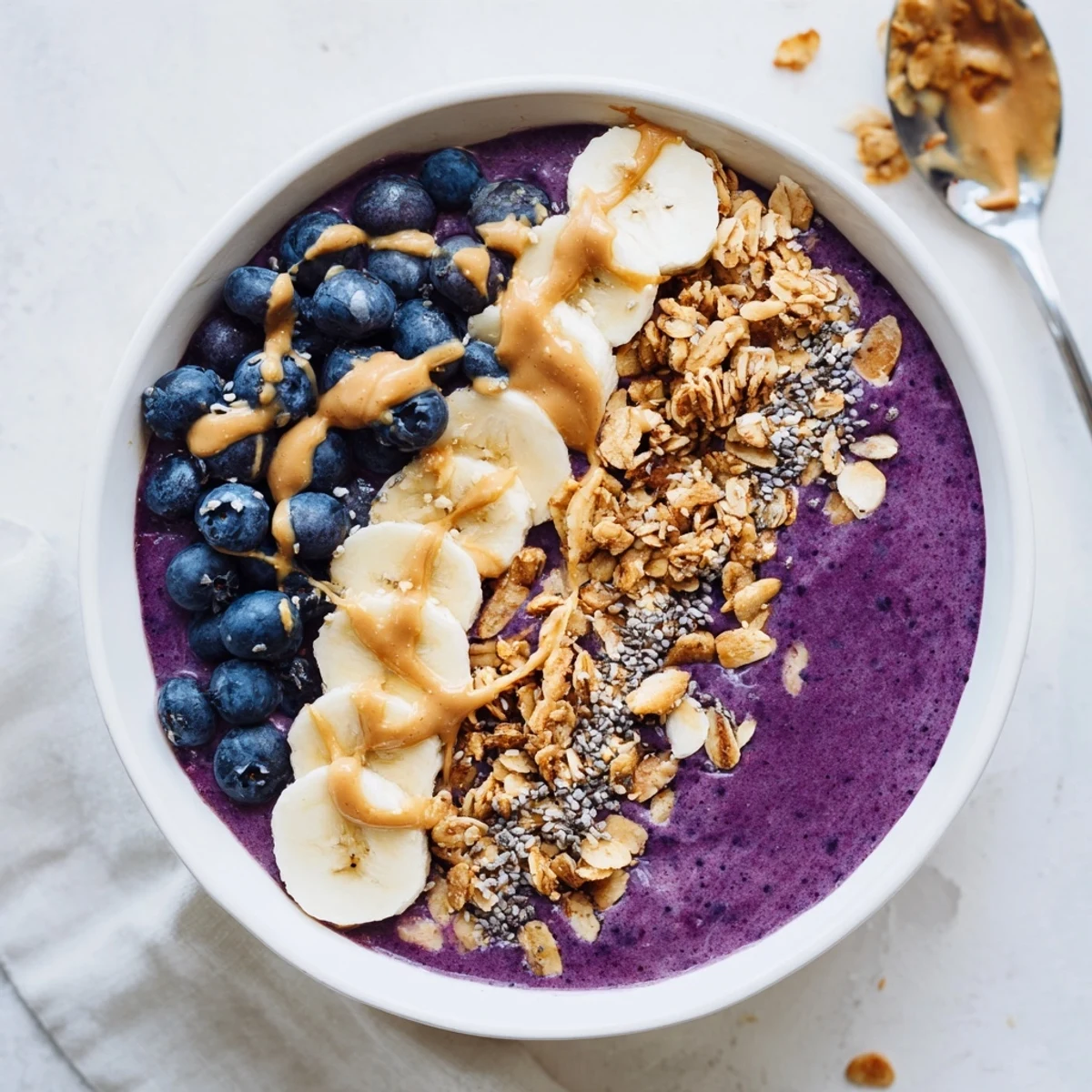 Creamy blueberry cashew vanilla smoothie bowl topped with crunchy golden granola clusters and fresh fruit
