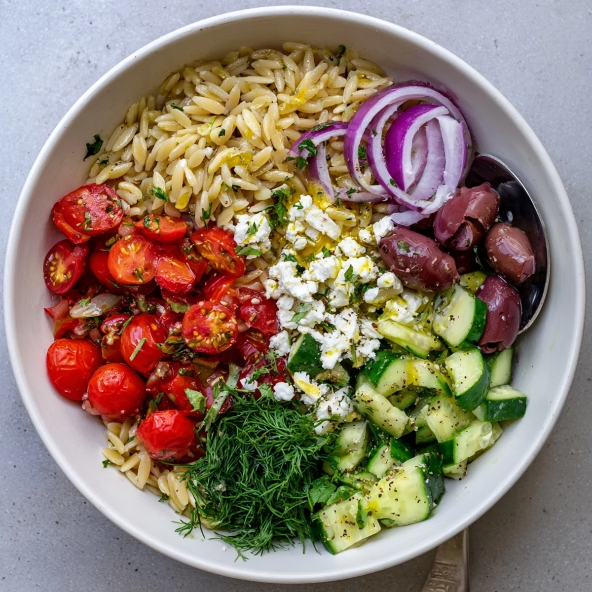 Colorful Mediterranean roasted tomato orzo grain bowl topped with fresh herbs and feta cheese