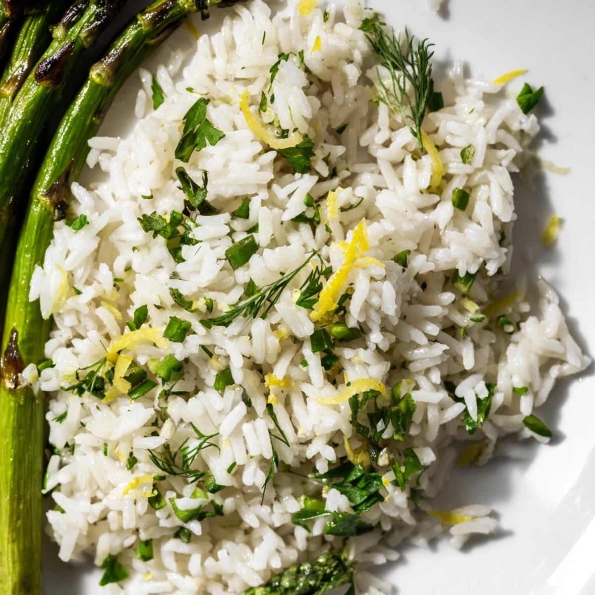 Golden citrus-infused rice mingled with green parsley and dill beside tender grilled asparagus stalks