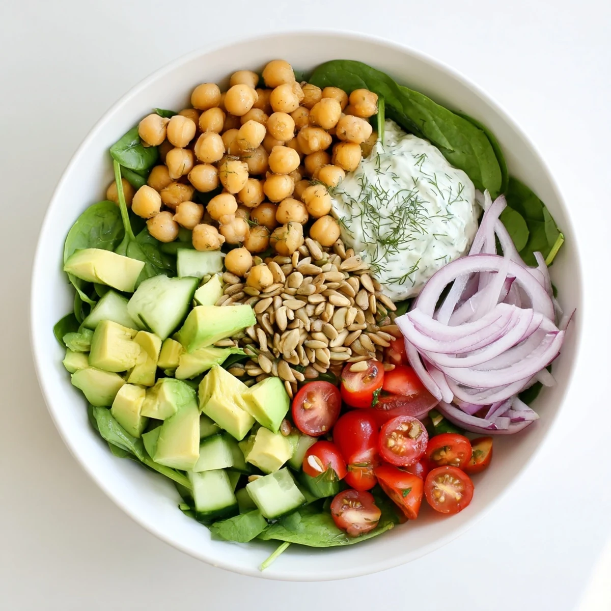 Protein-packed avocado spinach chickpea salad arranged in a bowl with cherry tomatoes and cucumber