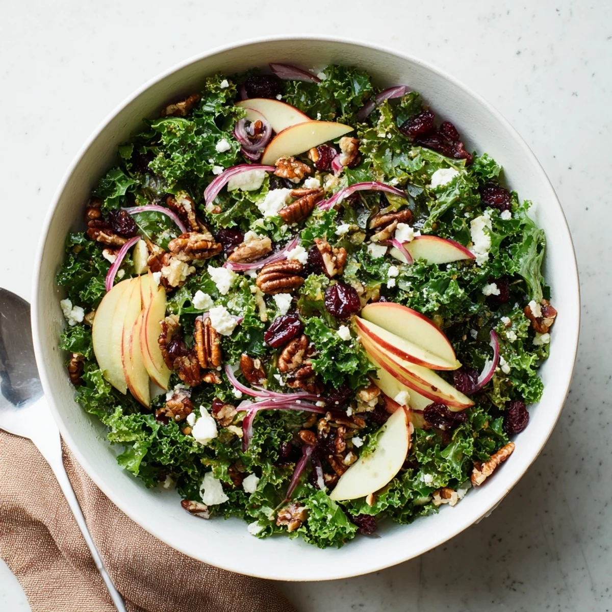 Colorful shaved kale apple pecan salad bowl drizzled with sweet maple dressing