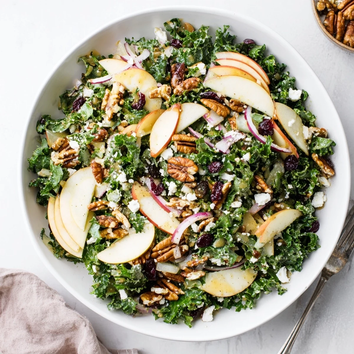 Vibrant kale apple pecan salad arranged in a bowl with glossy maple coating