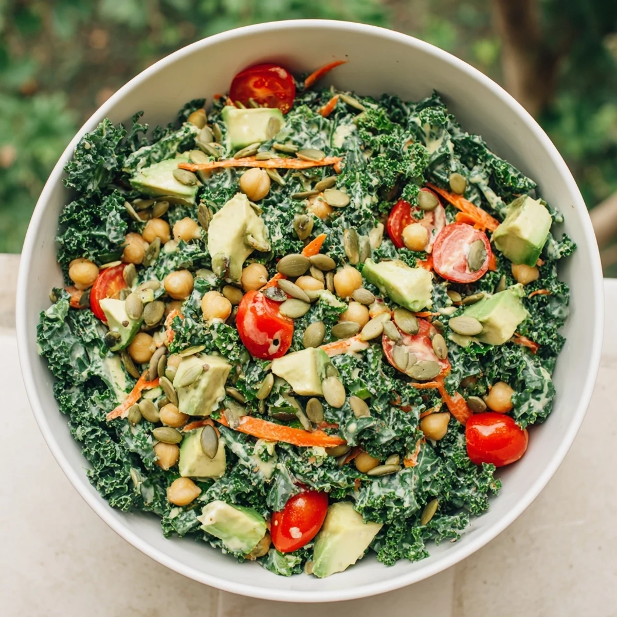 Fresh vegan salad bowl featuring chopped kale chickpeas avocado chunks and golden pumpkin seed topping