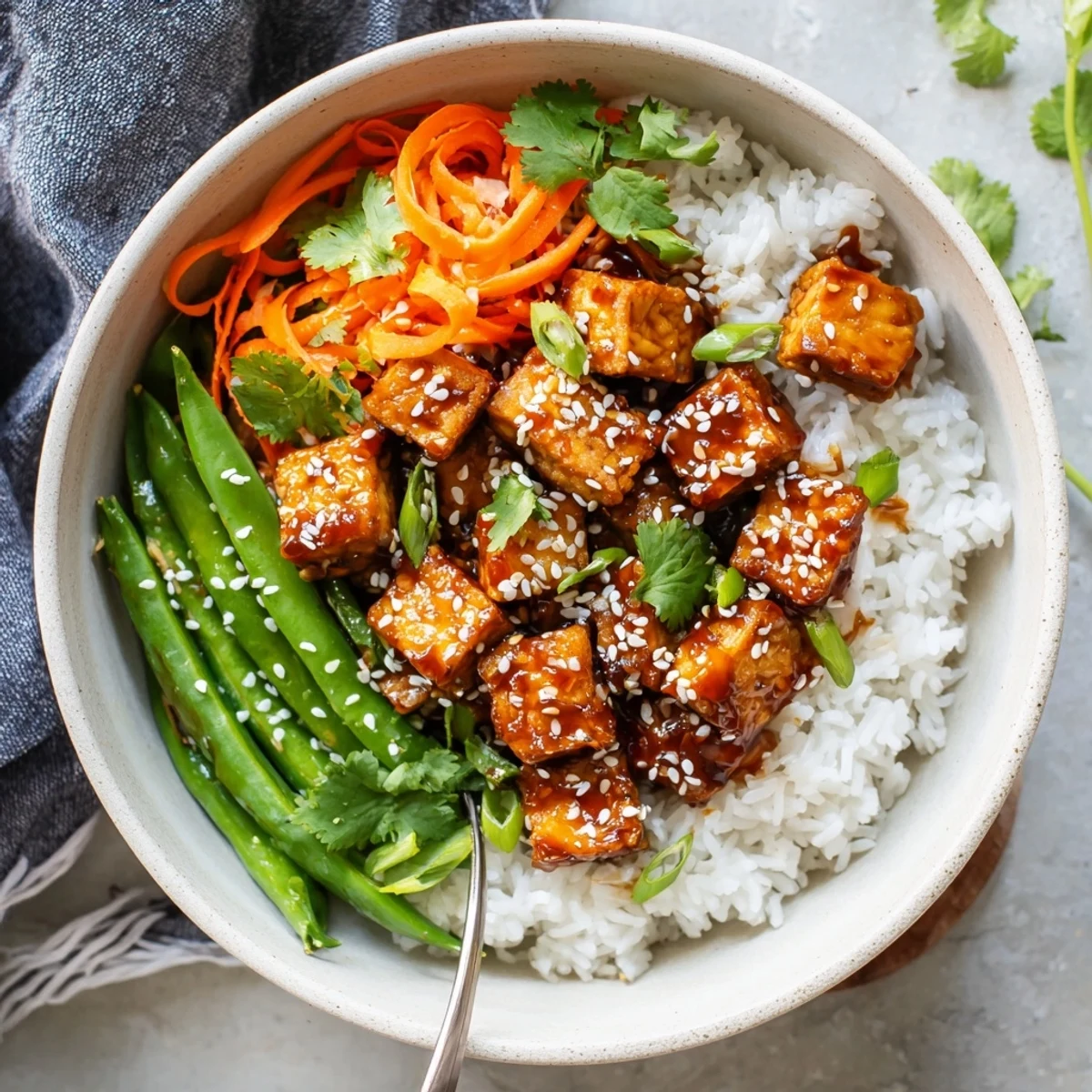 Golden caramelized maple chili tempeh cubes glisten atop fluffy white rice in this colorful vegan bowl