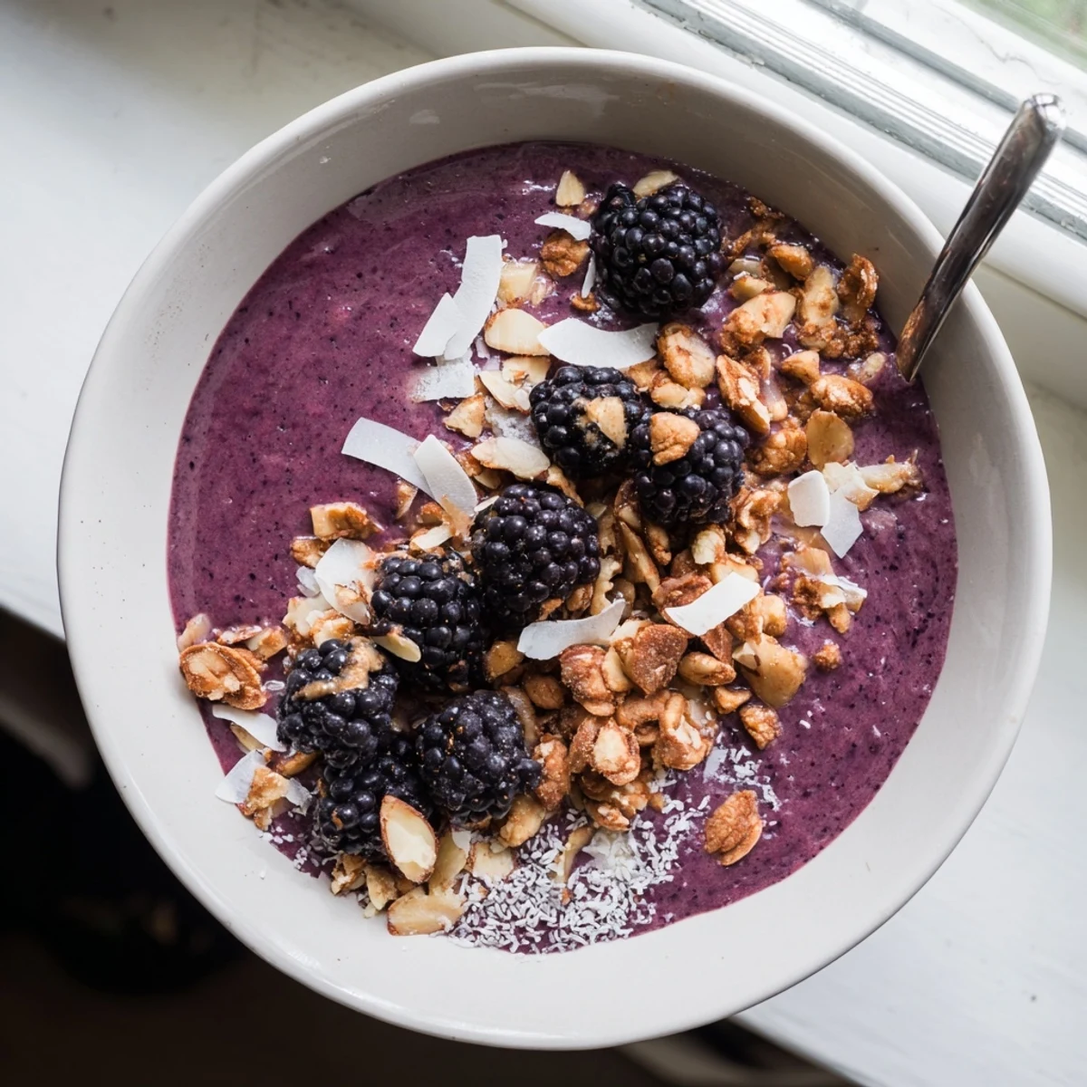 Thick smoothie bowl recipe featuring blackberries, coconut, vanilla, and maple glazed almond clusters