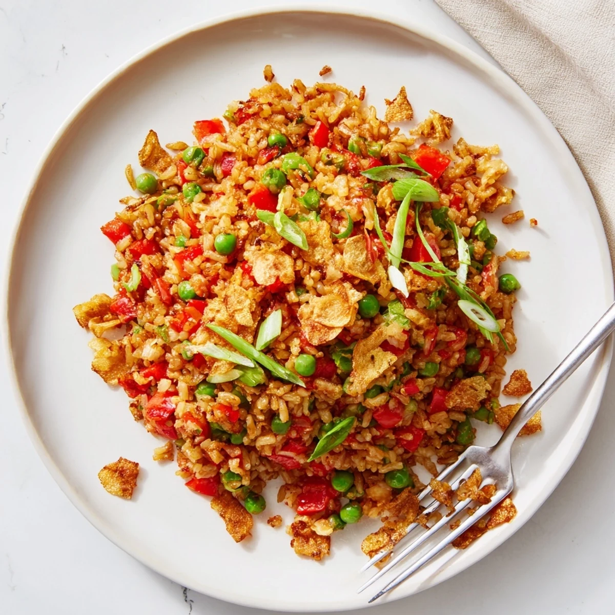 Steamy plate of garlic chili crisp fried rice scattered with vibrant red peppers and fragrant sliced scallions