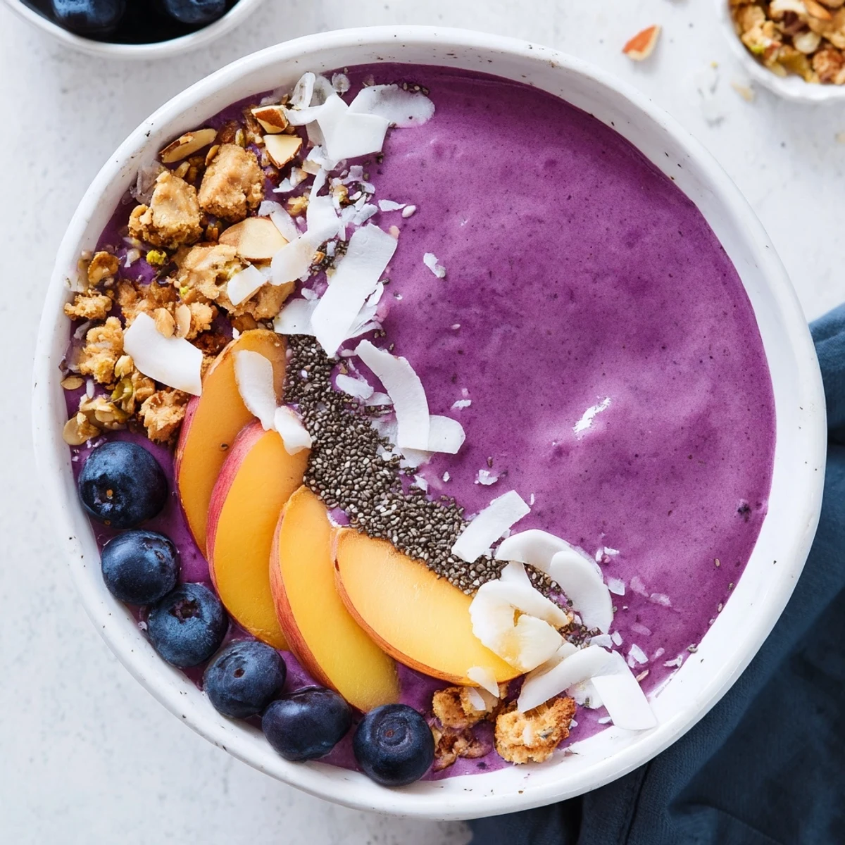 Vibrant breakfast bowl with blended blueberry peach almond base and assorted crunchy toppings