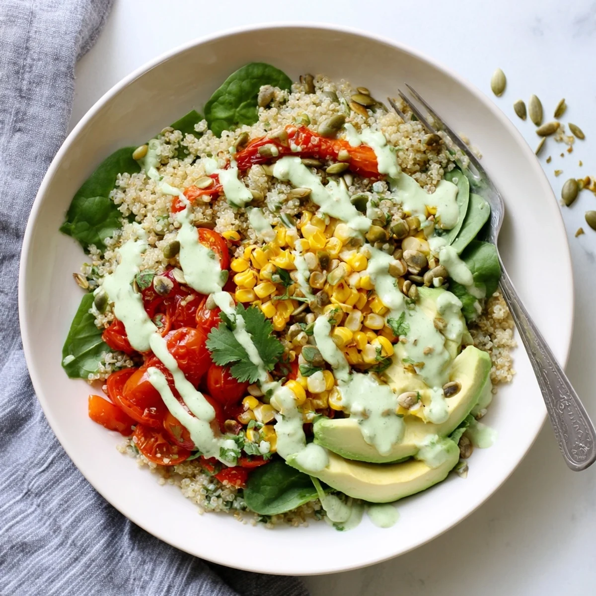 Colorful roasted sweet corn avocado quinoa grain bowl drizzled with tangy white lime crema