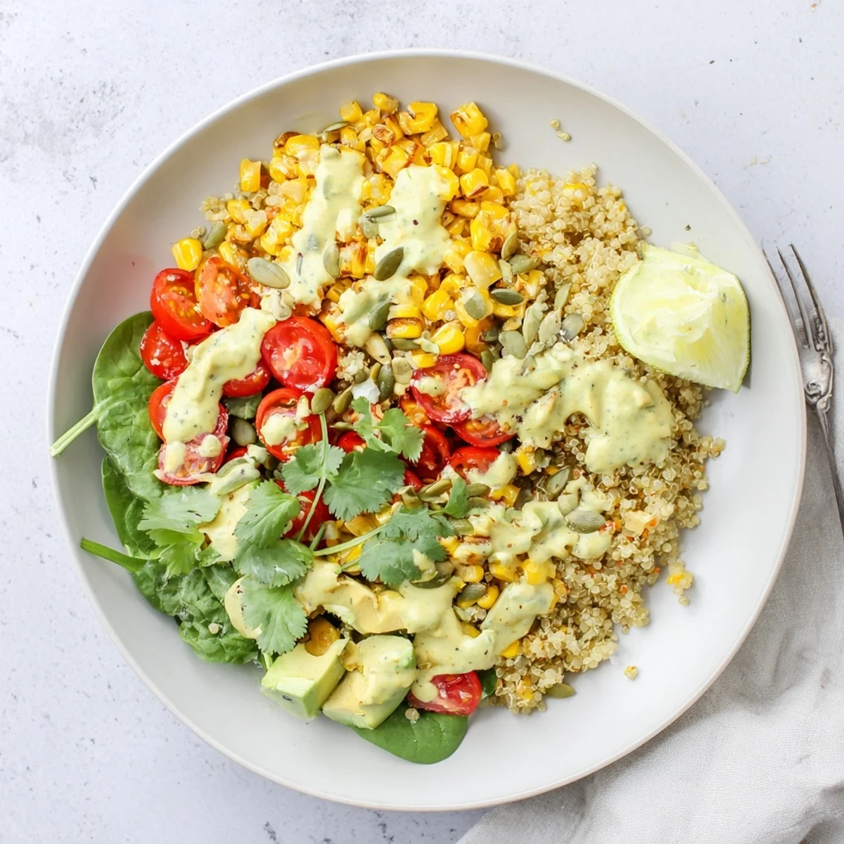 Roasted sweet corn avocado quinoa grain bowl topped with cherry tomatoes and creamy lime dressing