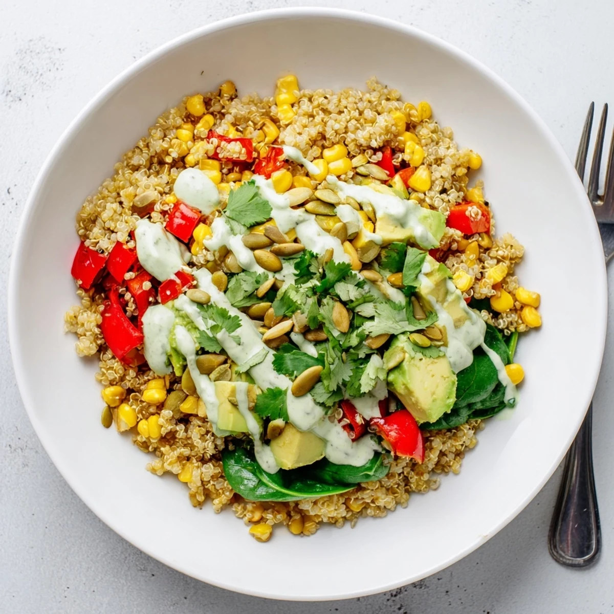Golden roasted sweet corn avocado quinoa grain bowl with fresh avocado slices and lime crema