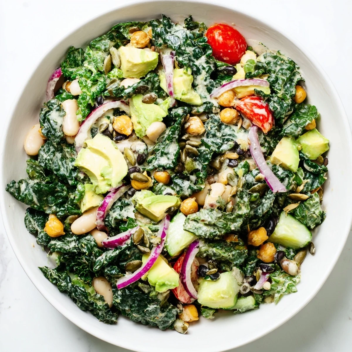 Vegan gluten-free white bean kale salad bowl drizzled with tangy lemon tahini dressing and crunchy seeds