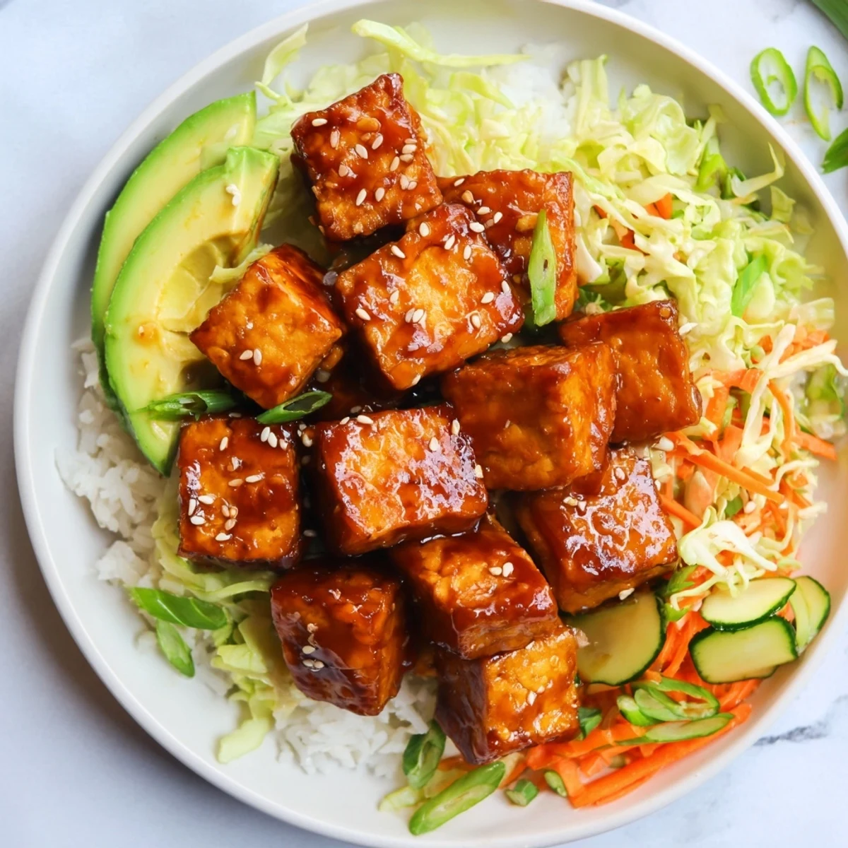 Crispy maple soy tofu vegan bowl topped with sesame cabbage and fresh avocado slices