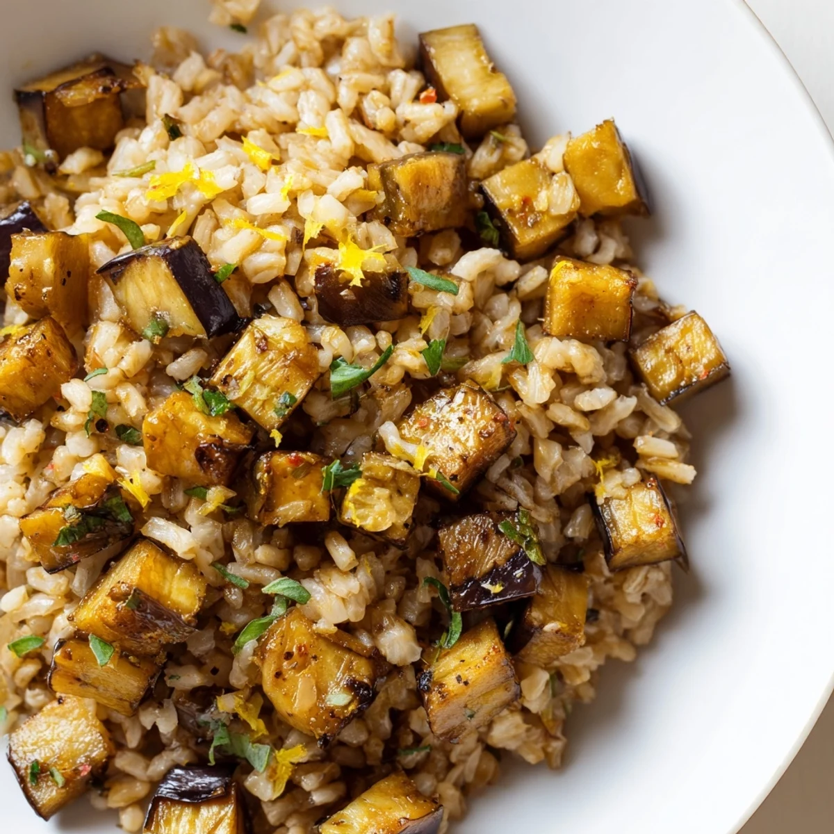Steaming garlic herb brown rice dish with caramelized eggplant cubes in cast iron skillet