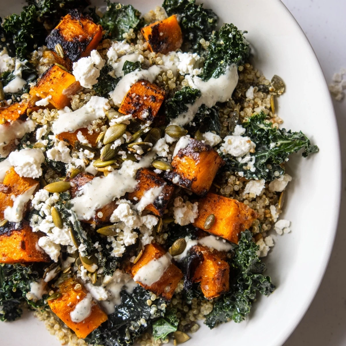 Roasted butternut squash kale quinoa grain bowl drizzled with creamy sage tahini dressing