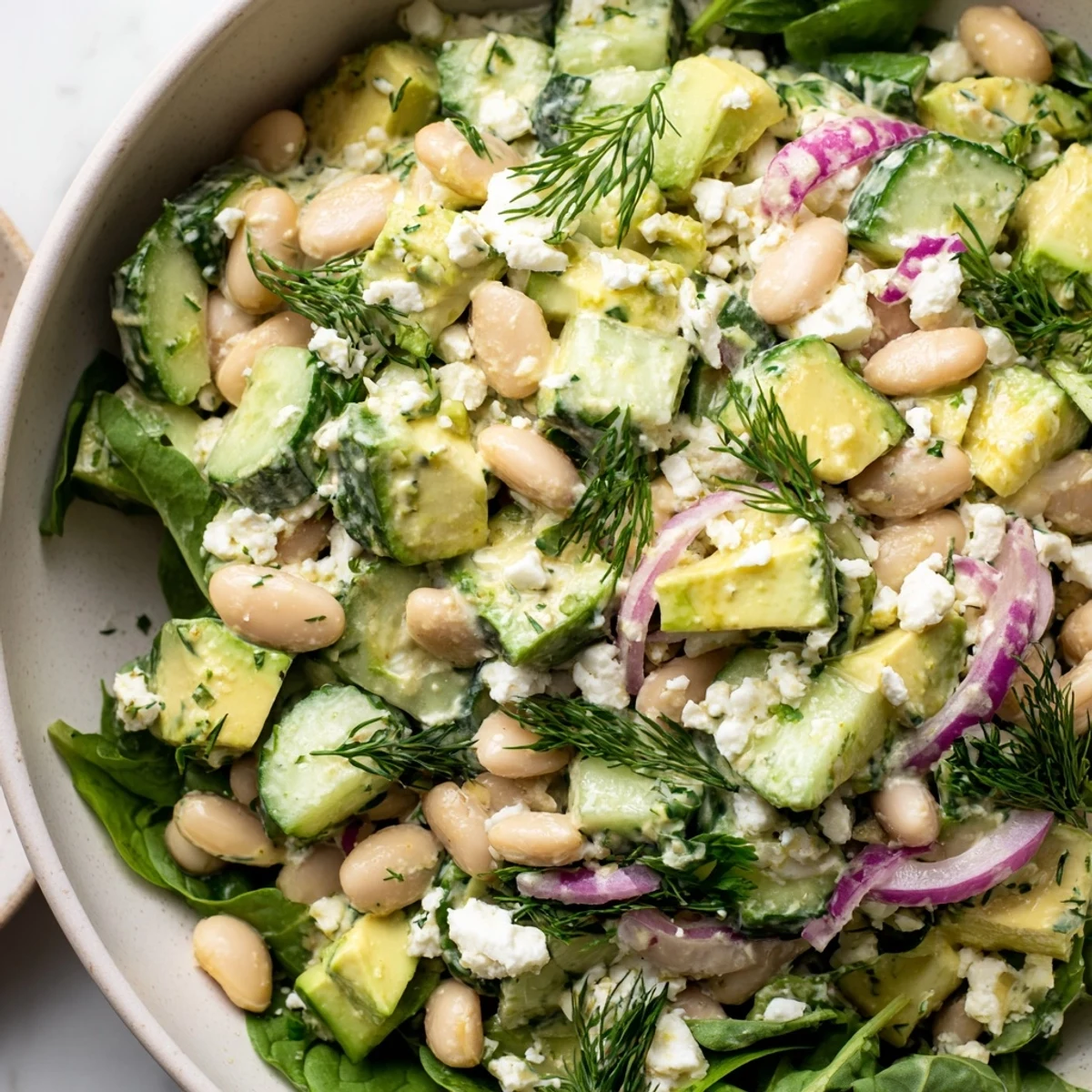 Vibrant white bean salad with diced avocado, crisp cucumber, and tangy yogurt dill dressing