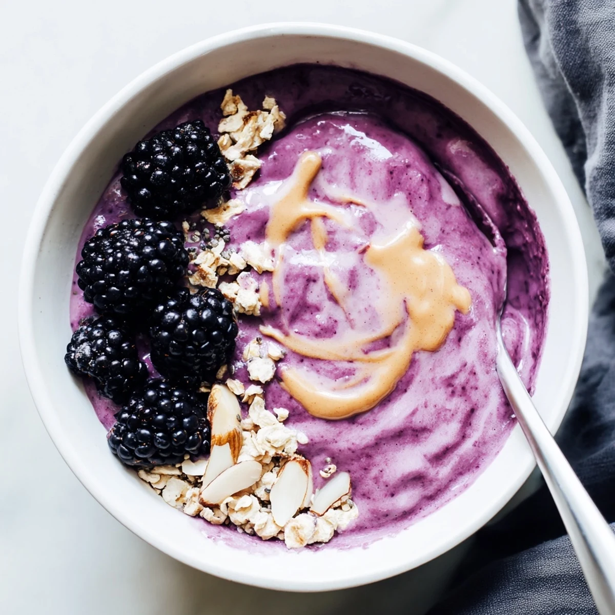 Blackberry Vanilla Oat Smoothie Bowl with Almond Butter Swirl, creamy, topped with granola