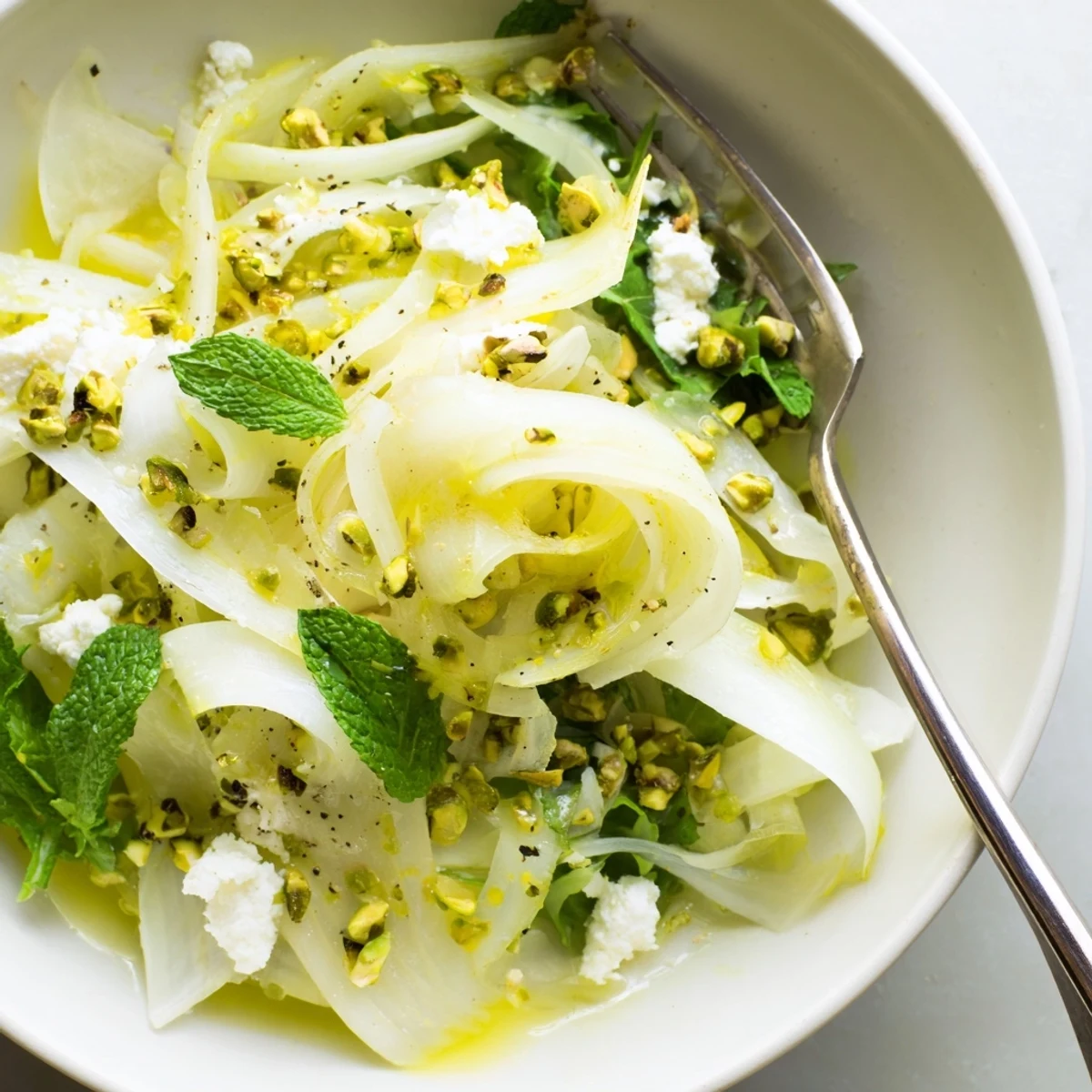 Peppery arugula and herbs in Shaved Fennel Pear Salad Bowl with Pistachio Vinaigrette