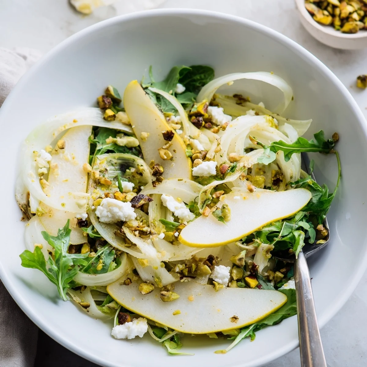 Bright citrus-dressed greens served as starter, Shaved Fennel Pear Salad Bowl with Pistachio Vinaigrette