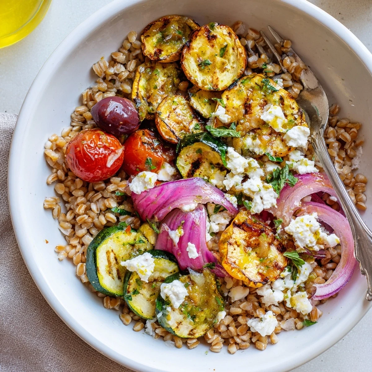 Bright Mediterranean Roasted Zucchini Farro Grain Bowl with Feta, crisp cucumber and cherry tomatoes