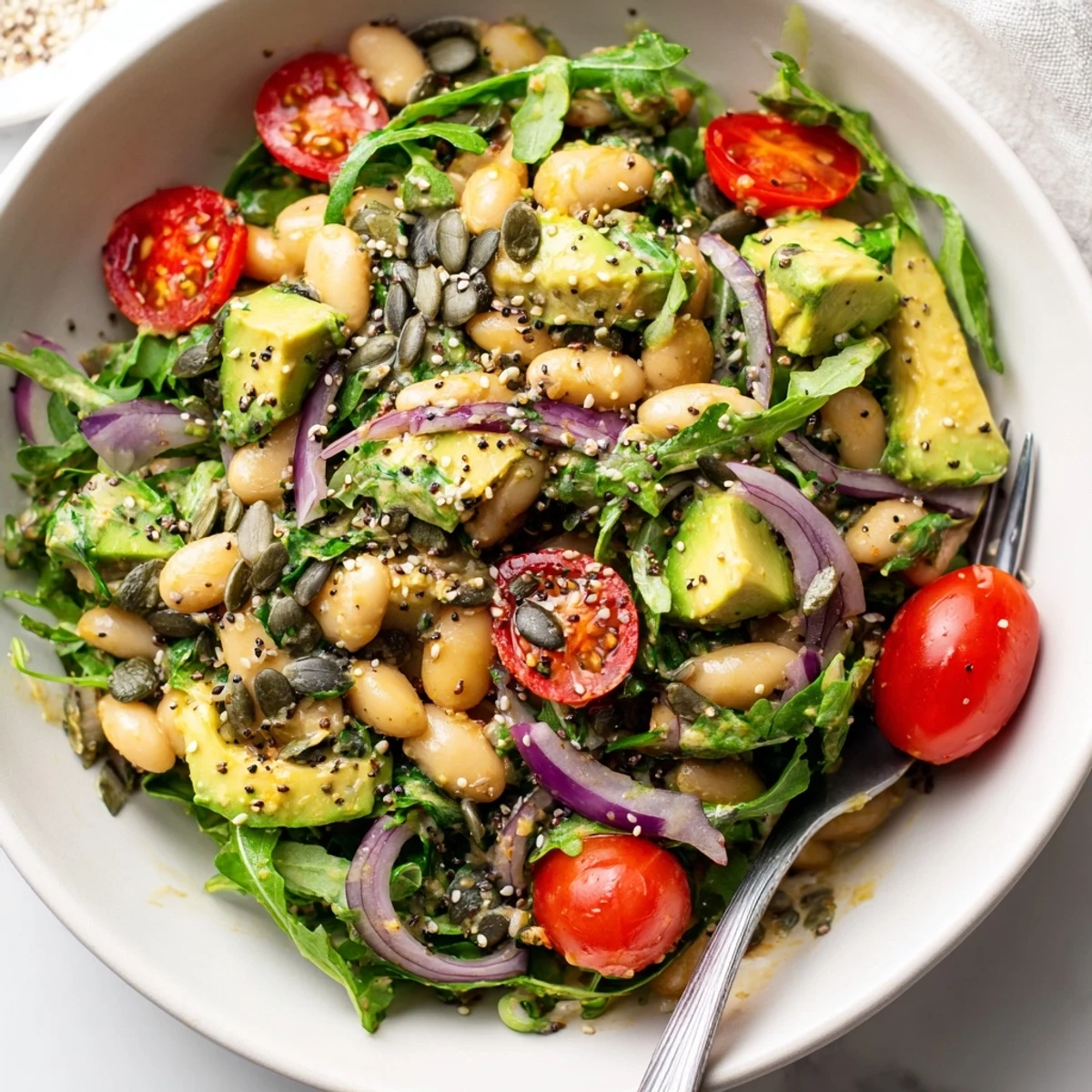 Creamy Avocado Arugula White Bean Salad Bowl with Seeds, tossed and ready to serve.