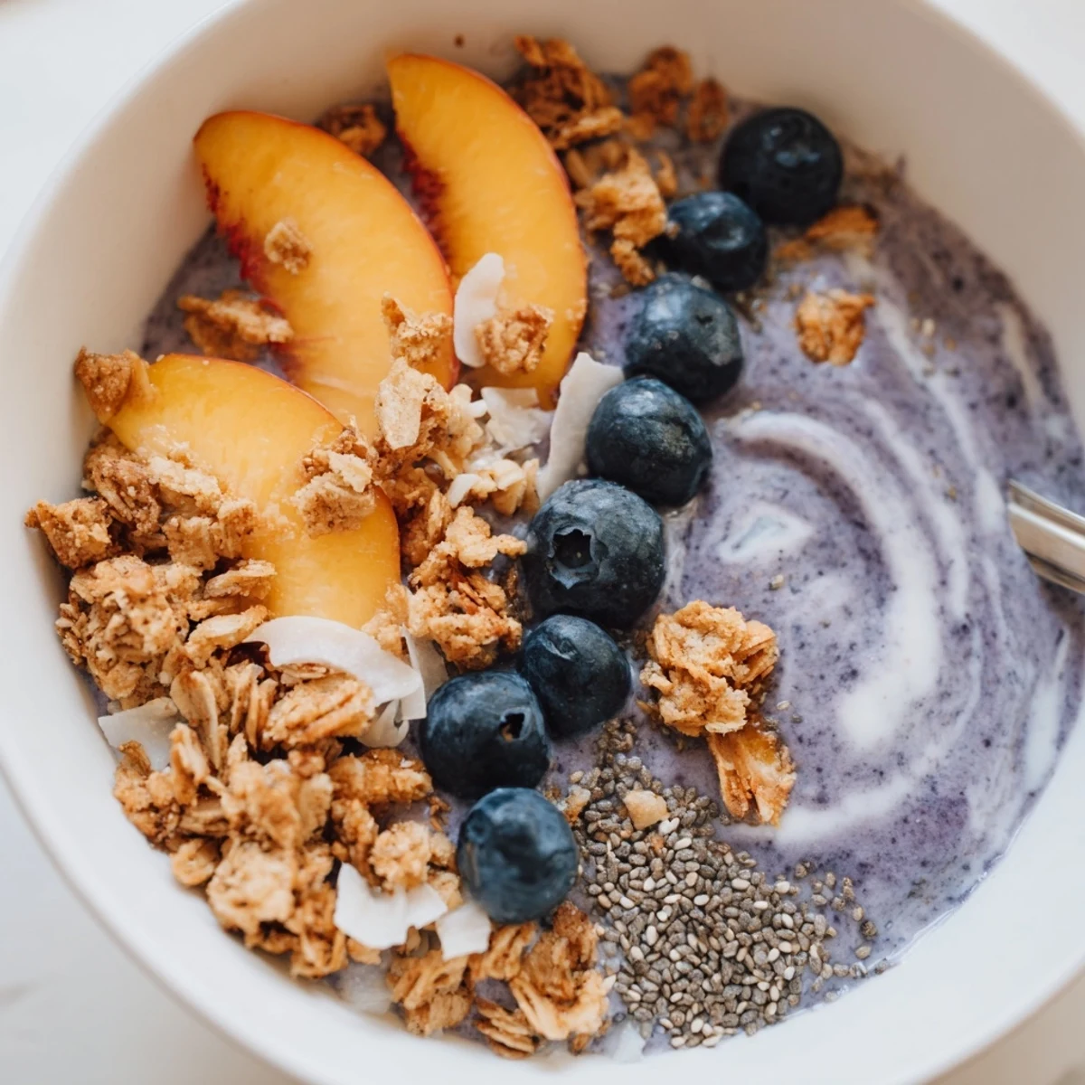Blueberry Peach Coconut Smoothie Bowl with Granola Clusters, creamy purple swirls, crunchy topping.