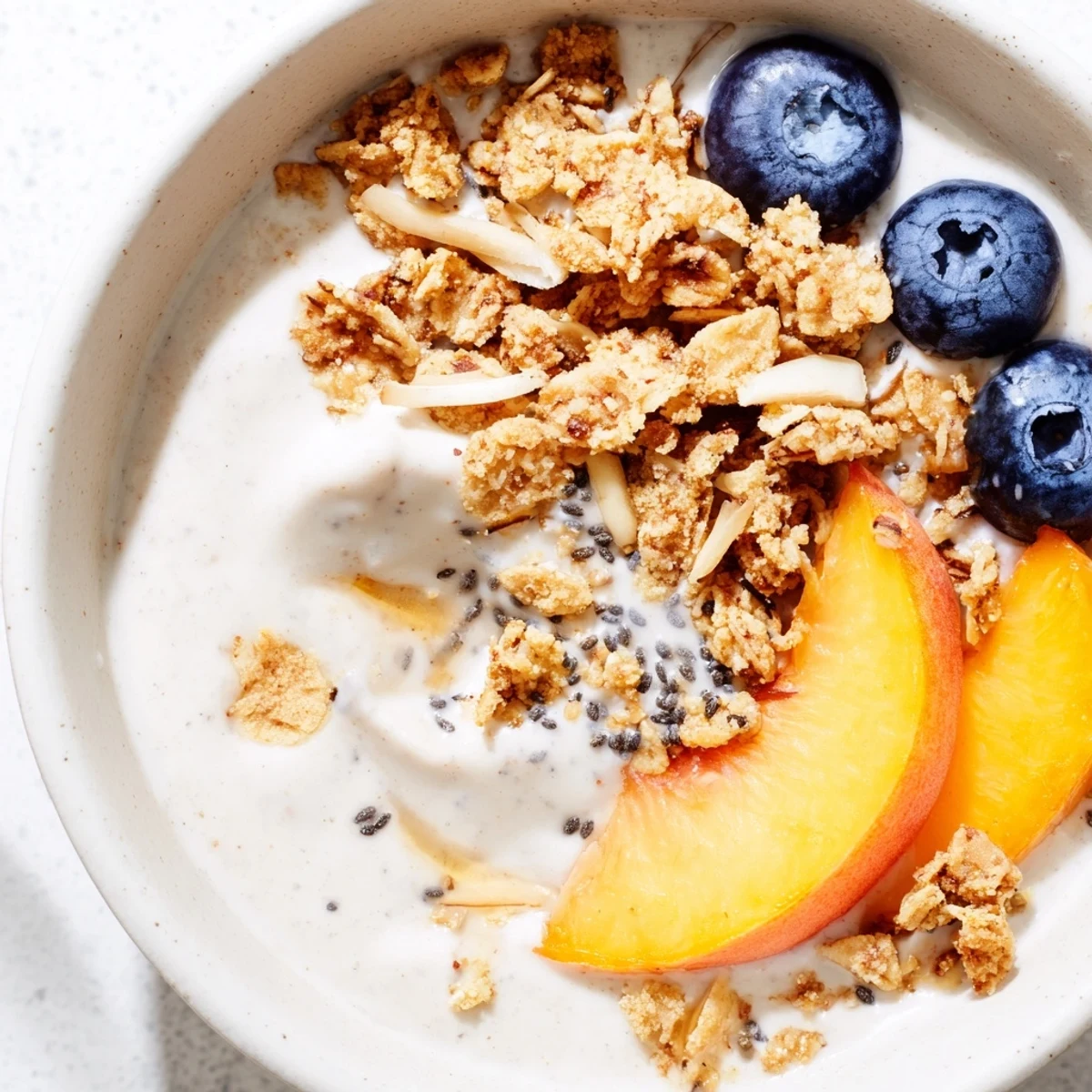 Silky chilled bowl — Blueberry Peach Coconut Smoothie Bowl with Granola Clusters.