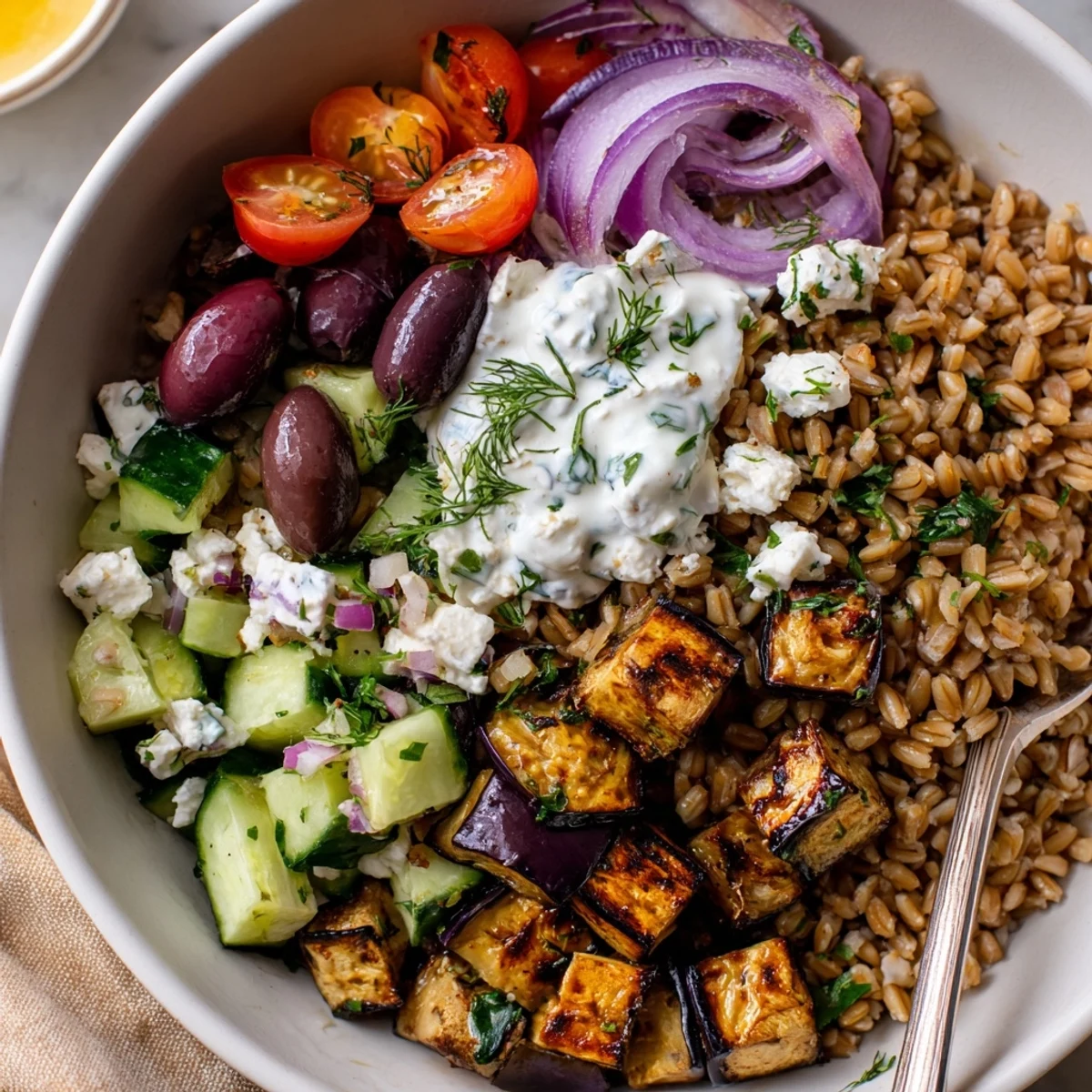 Warm, hearty Mediterranean Roasted Eggplant Farro Grain Bowl with Yogurt and lemon.