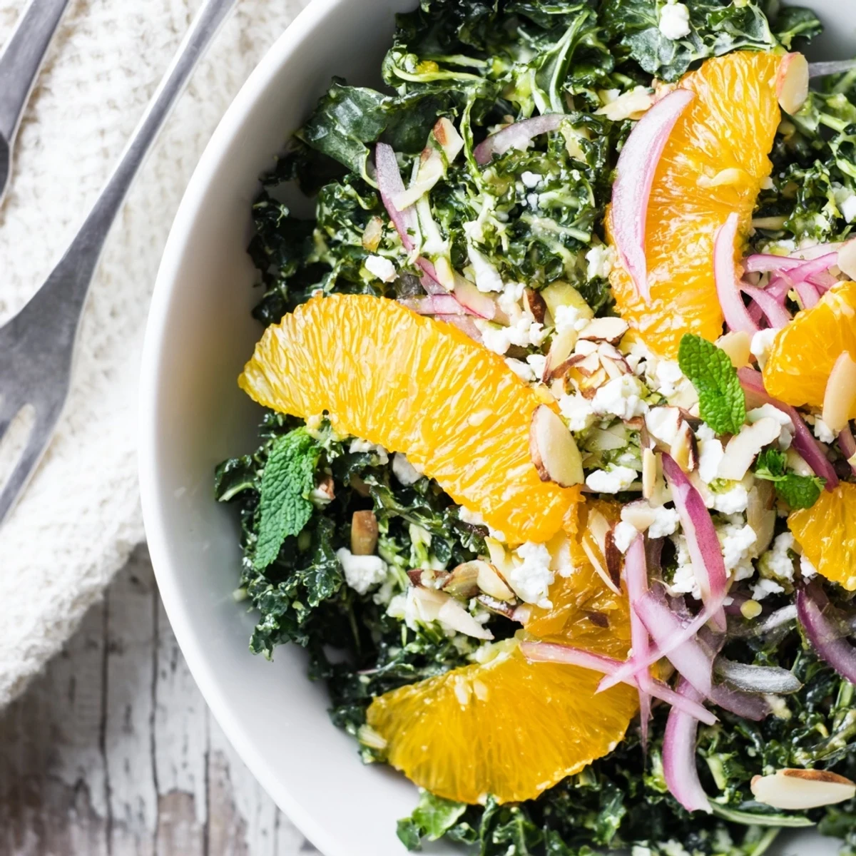 Shaved Kale Orange Almond Salad Bowl with Citrus Dressing, bright oranges and crunchy almonds.
