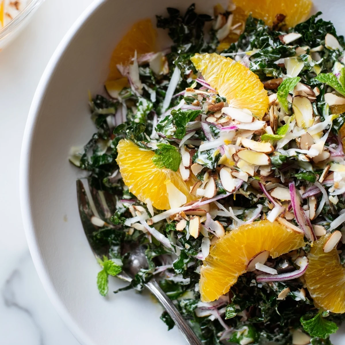 Shaved Kale Orange Almond Salad Bowl with Citrus Dressing served in a wooden bowl.