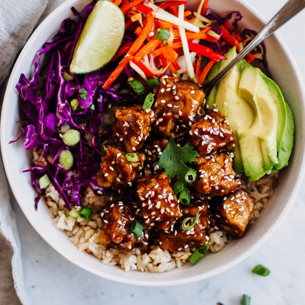 Bright lime, crunchy cabbage highlight Sticky Ginger Soy Tempeh Vegan Bowl with Sesame Slaw