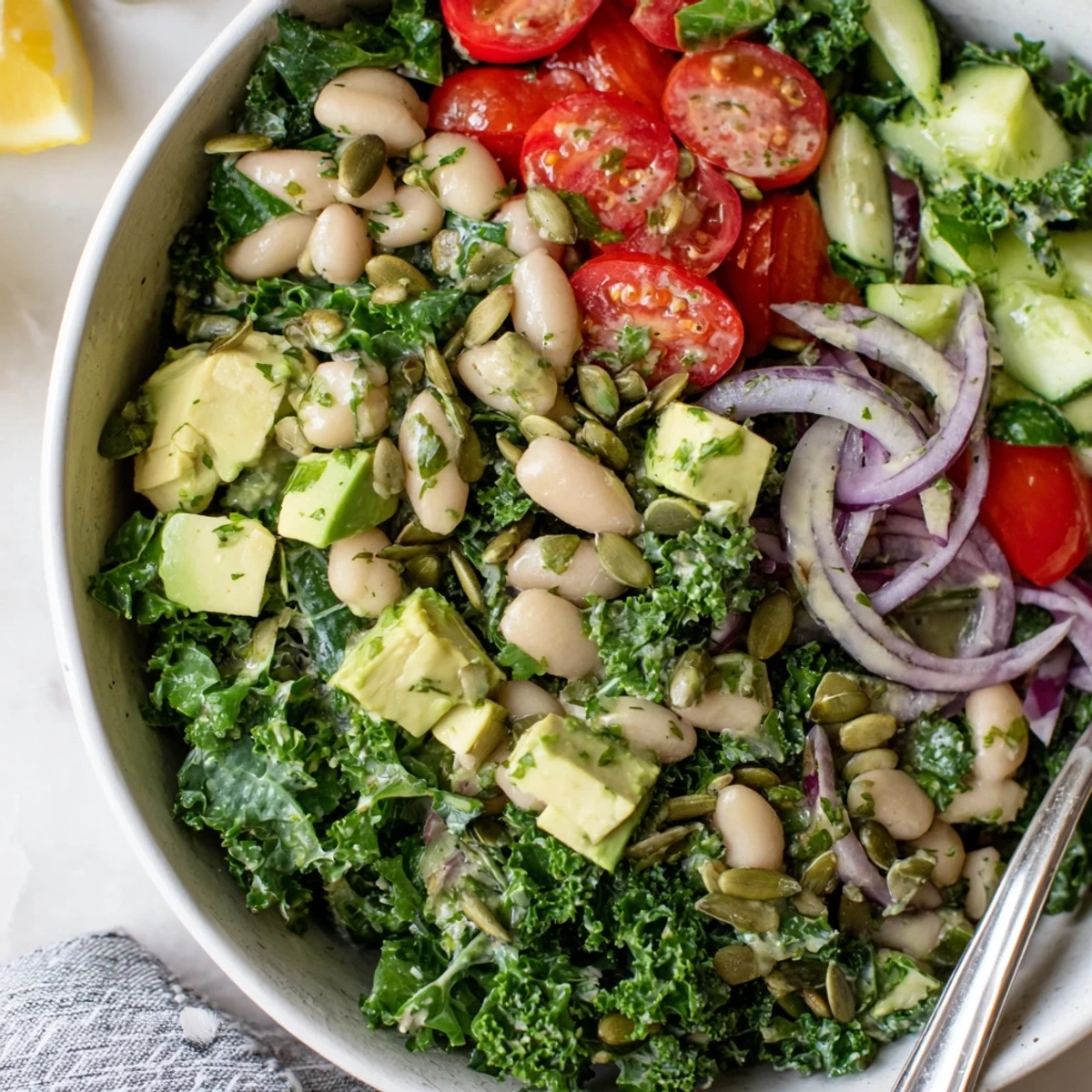 Bright lemon tahini coats Creamy Avocado White Bean Kale Salad Bowl with Fresh Herbs.