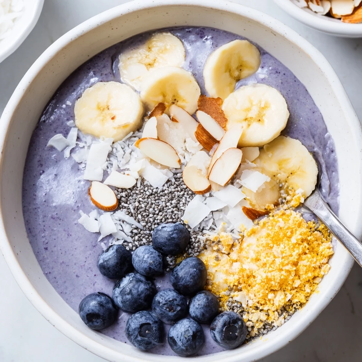 Blueberry Banana Almond Smoothie Bowl with Coconut Crunch served chilled with fresh bananas