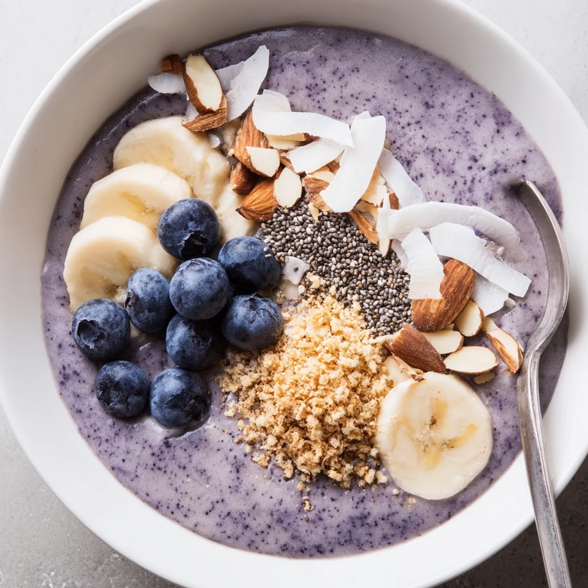 Blueberry Banana Almond Smoothie Bowl with Coconut Crunch, creamy base, crunchy granola garnish